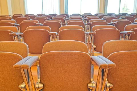 Empty rows of brown cushioned chairs in a bright conference or lecture room Stock Photos