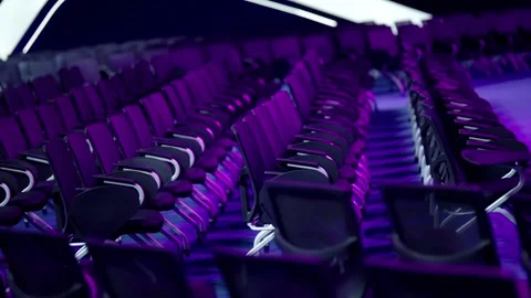 Empty rows of modern black chairs with metal legs line a large auditorium, seen Stock Footage 325669214