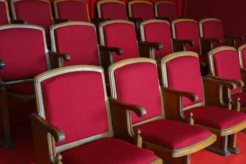 Empty rows of retro red theater or cinema seats with red upholstery. Stock Photos