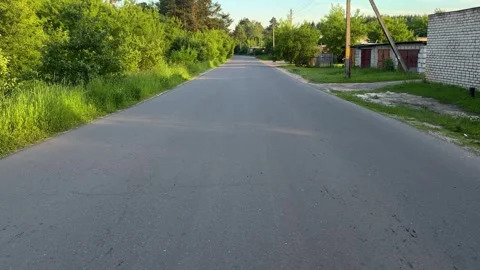 Empty rural asphalt road passing through green village at sunset Stock Footage 337434475