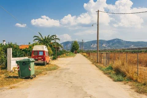 Empty rural road going through prairie under cloudy sky in Greece, Corinth. V Stock Photos
