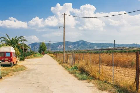 Empty rural road going through prairie under cloudy sky in Greece, Corinth. V Stock Photos