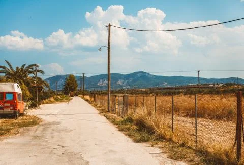 Empty rural road going through prairie under cloudy sky in Greece, Corinth. V Stock Photos