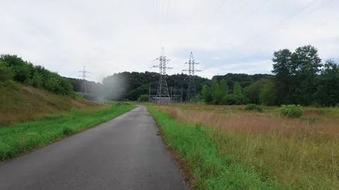 Empty Rural Road Leading to Power Substation Surrounded by Fields and Forest Stock Footage 345686958