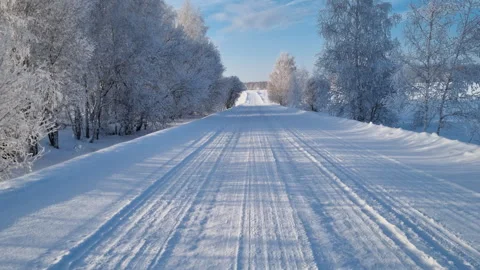 An empty rural snowy road surrounded by forest in the winter day.  Stock Footage 327120117