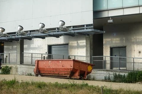 Empty rust colored dumpster behind a large building Stock Photos