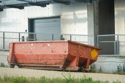 Empty rust colored dumpster behind a large building Stock Photos