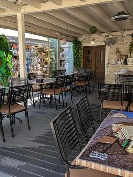 Empty rustic restaurant patio with black chairs, wooden tables, and stone wal Stock Photos