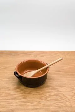 Empty rustic terracotta kitchen bowl and spoon on a wooden tabletop Stock Photos