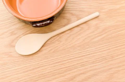 Empty rustic terracotta kitchen bowl and spoon on a wooden tabletop Stock Photos