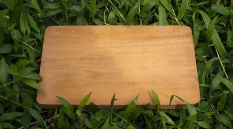 Empty Rustic Wooden Tabletop Mockup Surrounded by Green Grass Background Stock Photos