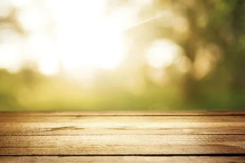 Empty rustic wooden texture of old wood table top, blur against green park with Stock Photos