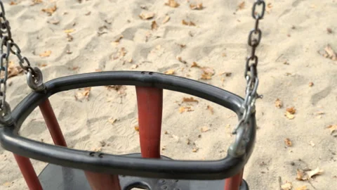 An empty, sad, children's swing moving in the autumn of the year. Video stock 106532551