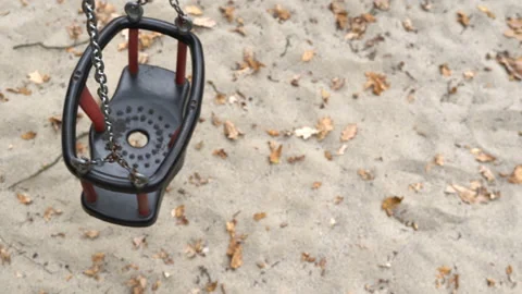 An empty, sad, children's swing moving in the autumn of the year. Stock-Footage 136491889
