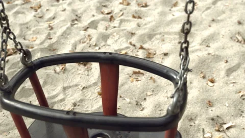 An empty, sad, children's swing moving in the autumn of the year. Stock-Footage 136492253