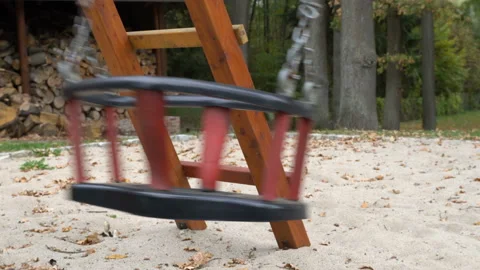 An empty, sad, children's swing moving in the autumn of the year. Stock-Footage 136492481