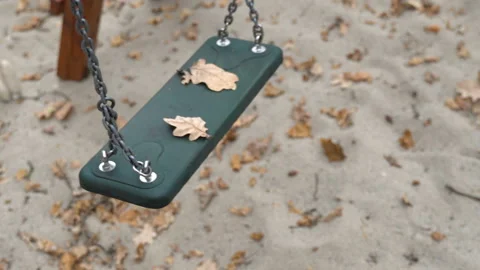 An empty, sad, children's swing moving in the autumn of the year. Stock Footage 136493563