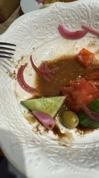 Empty salad plate with fork showing remnants of tomato, cucumber, and pickl.. Stock Photos