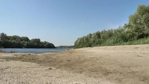 An empty sandy beach with a bald man riding a bicycle along the river Stock Footage 284622457