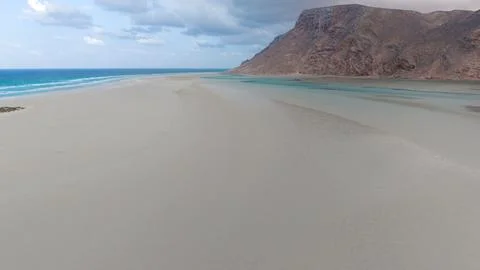 Empty sandy beach with blue lagoon and rocky mountains Stock Photos