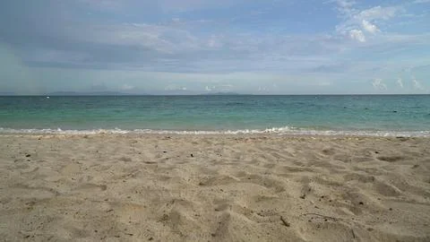 Empty sandy beach with blue ocean and cloudy sky Stock Photos