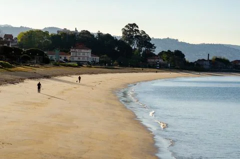 Empty sandy beach with calm waves near residential houses at sunrise, seren.. Foto stock
