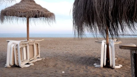 Empty sandy beach. Nice cloudy dramatic sky. Parasols opened, deckchairs folded Stock Footage 118852814