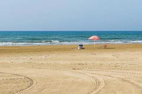 Empty sandy beach with one parasol on coastline Stock Photos