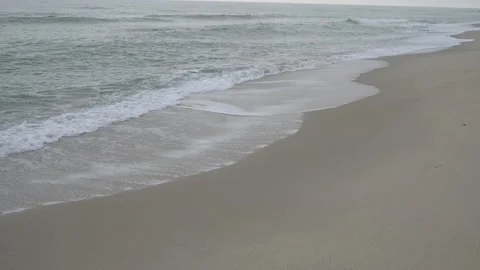 Empty sandy beach in off-season, calm sea waves washing shore under overcast sky 库存影片 329222368
