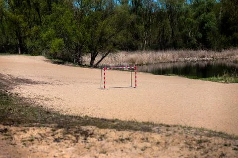 Empty sandy beach on the shore of a lake with a metal goal for playing football Foto stock