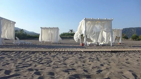 Empty sandy beach with sunbeds at sunset. Peaceful summer scene. Video stock 78752481