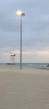 An empty sandy beach at sunset with a lifeguard tower and lantern Stock Photos
