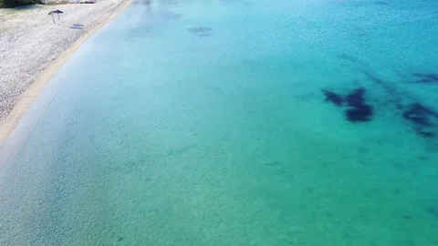 Empty sandy beach with two parasols and greenery by the clear sea. Aerial view Video stock 134852911