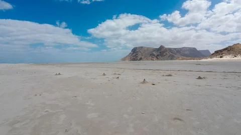 Empty sandy shore with mountains and blue cloudy sky Foto stock
