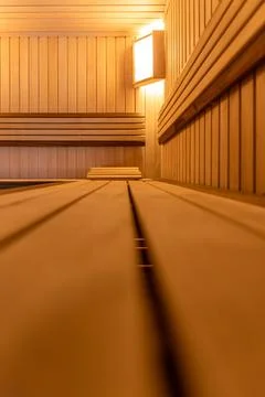 Empty sauna interior from bench level. Warm wooden room with ambient lighting Stock Photos