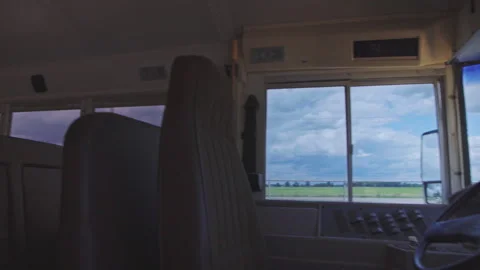 Empty school bus interior with dark storm clouds over fields outside Video stock 347731609