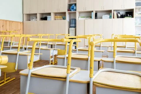 Empty school classroom with yellow desks stacked for cleaning after academi.. Stock Photos