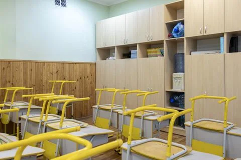 Empty school classroom with yellow desks and chairs stacked on top, reflect.. Stock Photos