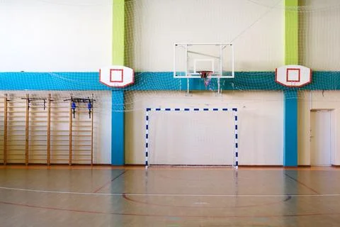 Empty school gym interior featuring basketball hoop and handball goal Stock Photos