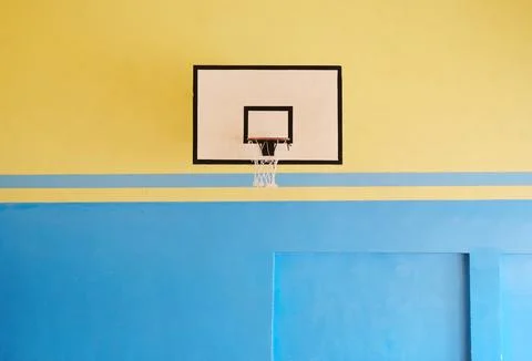 Empty school gym interior featuring a basketball hoop against a vibrant yellow Stock Photos
