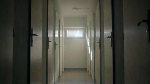 Empty school hallway with closed classroom doors and daylight at end Video stock 347221690