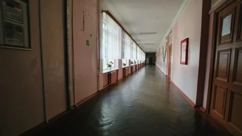 Empty school hallway with parquet floor, pink walls, radiators, and windows Stock Footage 316093044