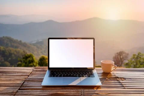 Empty screen laptop with cup of coffee and camera with mountain view 库存照片