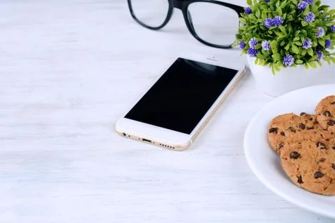 Empty screen mobile with plastic cup of coffee and cookies Stock Photos