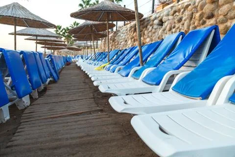 Empty sea beach with a flat row of sun beds and umbrellas at sunrise 스톡 사진
