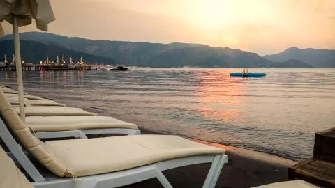 Empty sea beach with rows of sunbeds at the sunset 스톡 사진