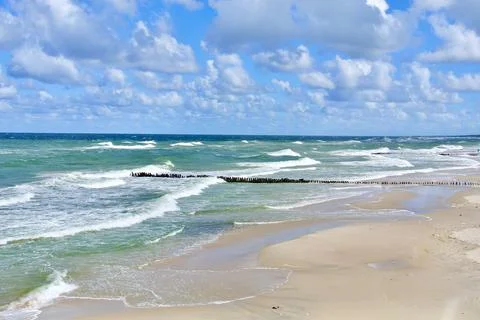 Empty seashore with textured vivid waves under moody colourful skyline. Bal.. Stock Photos