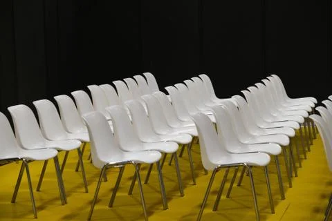 Empty seats in rows audience room white chairs yellow floor Foto stock