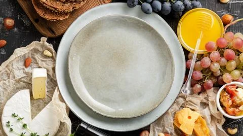 Empty serving plate in center frame made of honey grapes cheese snack other f Stock Photos
