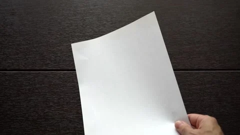 An empty sheet of white paper is placed on a wooden table. Stock Footage 156846492